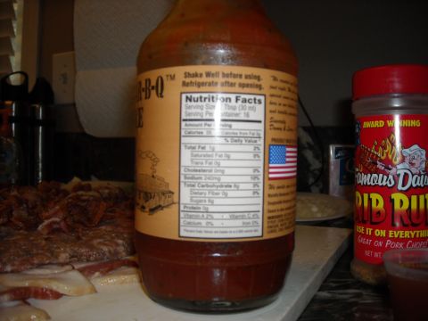 1979 Ford F-150 - A bottle of BBQ sauce sits on a counter next to a container of rib rub and raw meat.