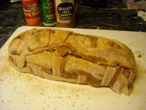1979 Ford F-150 - A meatloaf wrapped in bacon sits on a cutting board next to three bottles of seasoning.