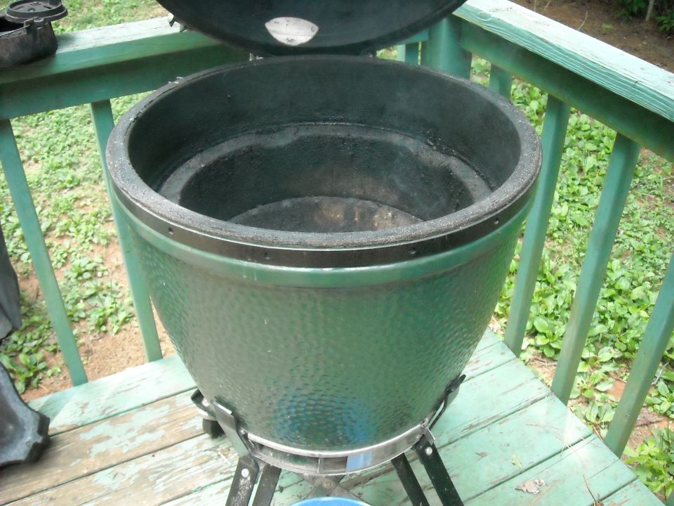 Green ceramic grill with lid open, sitting on a wooden deck