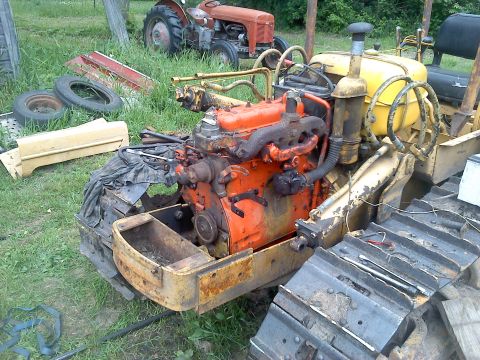 1963 Hummer H3 - The engine of a yellow tractor is visible, with an orange block and yellow tank. Another tractor is in the background.
