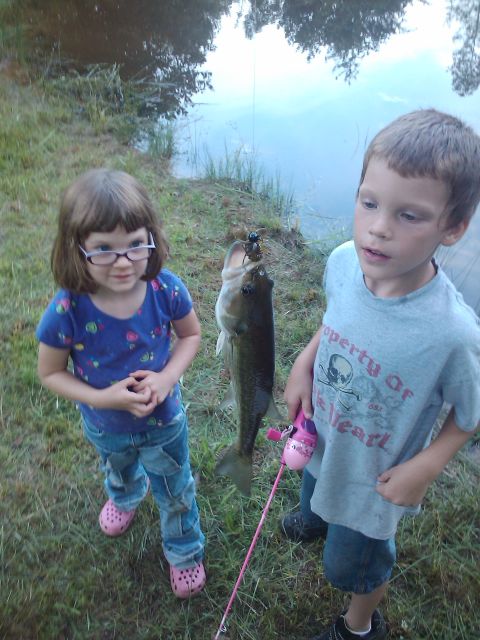 1989 Ford Bronco - A girl and a boy proudly display a large fish they caught while fishing by a pond.