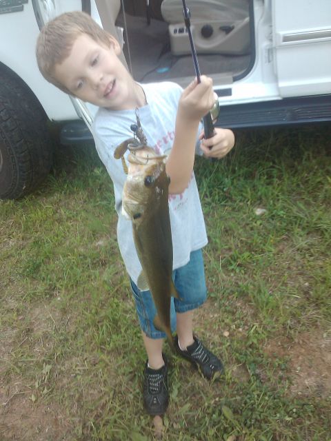 1989 Ford Bronco - A boy proudly displays a large fish he caught, with the side of a white SUV visible in the background.