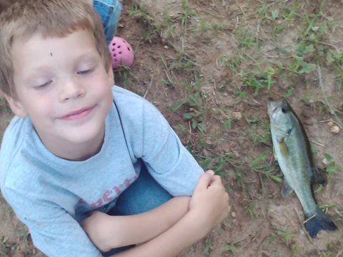 1989 Ford Bronco - A young boy smiles next to his catch of the day, a small fish lying on the dirt.