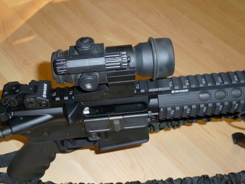 1992 Ford Mustang - Close-up of an assault rifle with a scope mounted on the rail system.