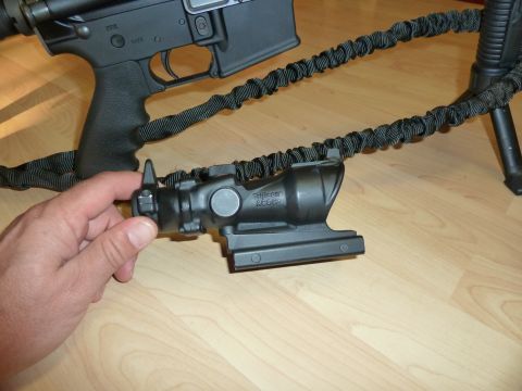 1992 Ford Mustang - A Trijicon ACOG scope is shown attached to an AR-15 rifle with a sling, resting on a wooden surface.