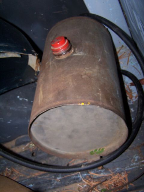 1973 Ford Bronco - A rusty cylindrical tank with a red cap and a black hose is shown, possibly an old fuel or air tank.