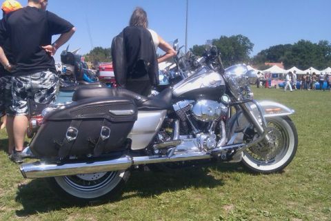 1991 Ford LTD Crown Victoria - A motorcycle is parked on a grassy field with people and tents in the background.