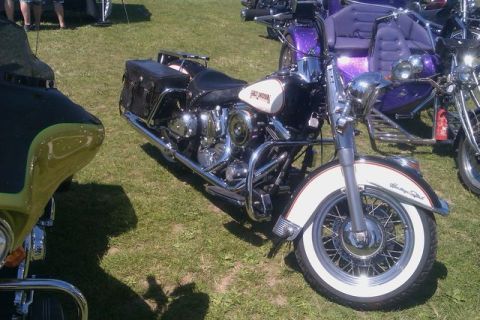 1991 Ford LTD Crown Victoria - A classic Harley-Davidson motorcycle is parked on a grassy field, with other vehicles visible in the background.
