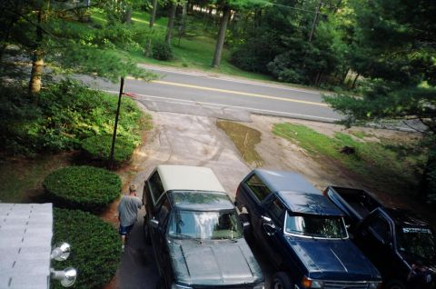 1994 Ford Bronco - Three SUVs, including a 1994 Ford Bronco, are parked on a driveway next to a road.