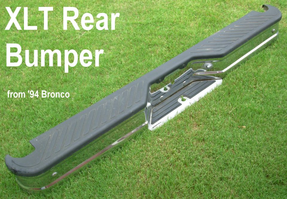 Black XLT rear step bumper from a 1994 Bronco lying on grass