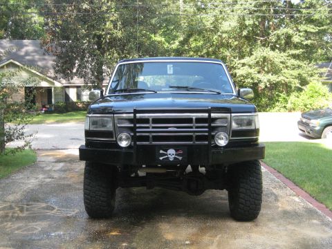 1993 Ford Bronco - Front view of a black SUV equipped with a bull bar and a decorative license plate frame a skull and crossbones.