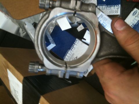 1993 Ford Bronco - A close-up view of a metal connecting rod, with packaging for Clevite parts in the background.