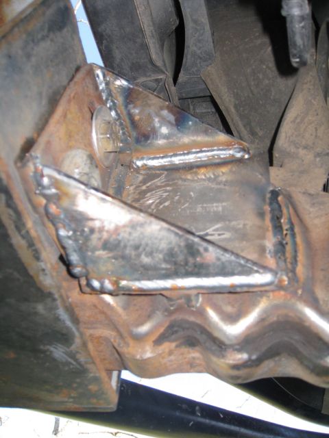 1994 Ford Bronco - Close-up view of custom metal brackets welded onto a vehicle's frame component.