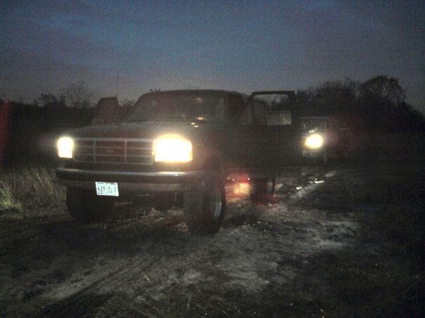 Dark 1992 Ford F-Series truck with headlights on and driver's door open