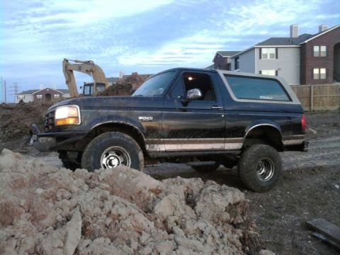 1994 Ford Bronco - A dark blue 1994 Ford Bronco with a lifted suspension navigates a construction site.