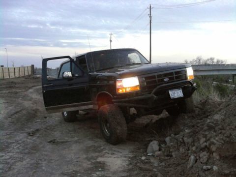 1994 Ford Bronco - Black Ford F-Series truck with driver's door open, parked on dirt incline. License plate reads 6ZP-2LT.