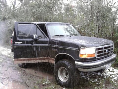 1994 Ford Bronco - Black 1994 Ford Bronco stuck in mud with the driver's door open.