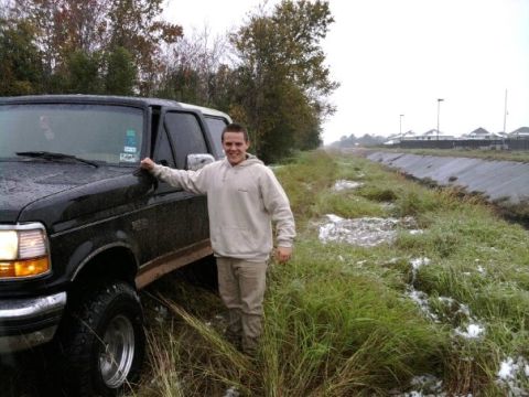 1994 Ford Bronco - Man poses with a black 1994 Ford Bronco on a cloudy day near a water channel.