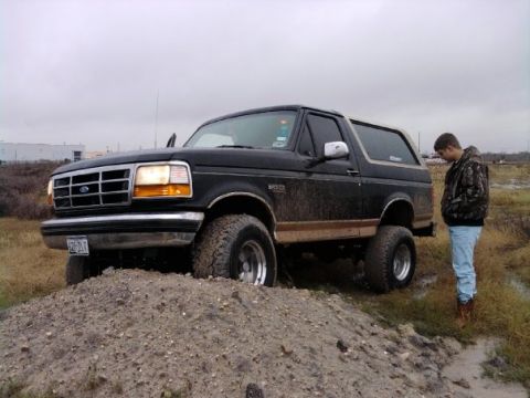 1994 Ford Bronco - A 1994 Ford Bronco is positioned on a dirt pile with a person standing nearby.