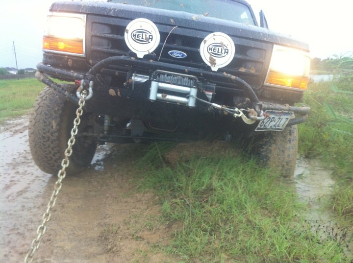 Black Ford Bronco with winch and auxiliary lights stuck in mud, front view