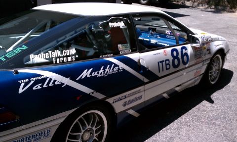 1990 Ford Probe - This heavily stickered race car, likely a Ford Probe, is seen from the side with racing decals and sponsor logos visible.