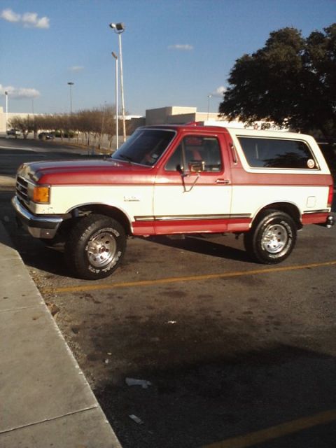 1989 Ford Bronco - This two-tone red and white Ford Bronco is seen from the side in a parking lot.