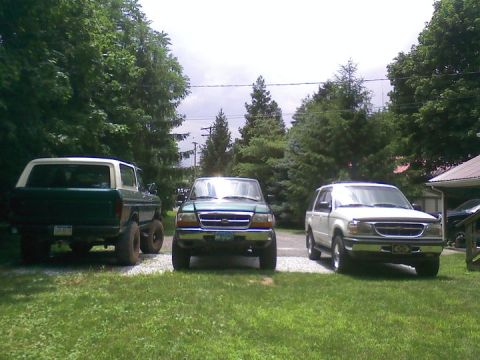 1979 Ford Bronco - A 1979 Ford Bronco is parked alongside two other SUVs in a yard on a cloudy day.