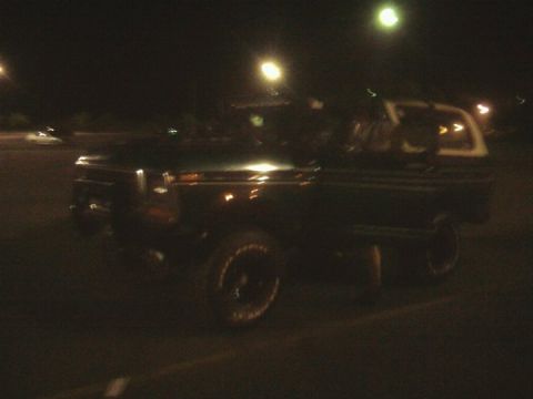 1979 Ford Bronco - This dark SUV with a white top is seen at night from a 3/4 front angle. The body style is consistent with a 1979 Ford Bronco.