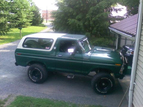 1979 Ford Bronco - Green 1978 Ford Bronco with white removable top parked on gravel driveway next to a house.