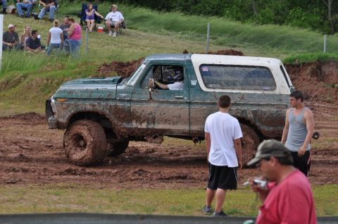 1979 Ford Bronco - A muddy 1978 Ford Bronco navigates a rough terrain event with spectators watching.