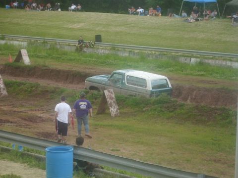 1979 Ford Bronco - A Ford Bronco is stuck in a muddy track with spectators in the background.
