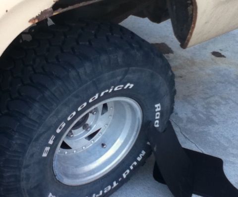 2006 Ford E350 - Close-up of a BFGoodrich Mud-Terrain tire and a rusted fender section of a vehicle.