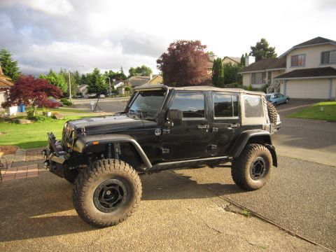 2008 Jeep Wrangler - Modified black Jeep Wrangler parked on a driveway in a suburban setting.