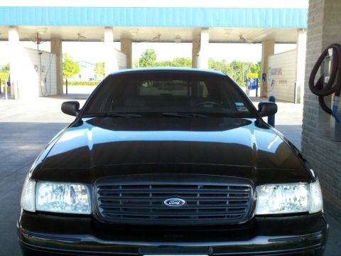 2000 Ford Crown Victoria - Front view of a black 2000 Ford Crown Victoria parked under a covered area.