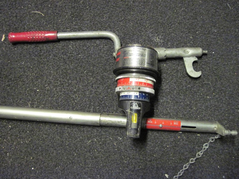 Metal automotive alignment tool with red handle and circular gauges