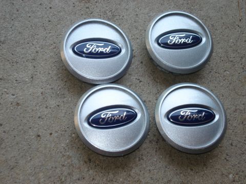2000 Ford Crown Victoria - Set of four Ford center caps with the classic blue oval logo are shown on a concrete surface.