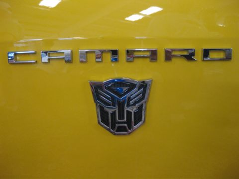 2011 Chevrolet Camaro - Close-up of a Camaro badge and Autobot logo on a yellow car.
