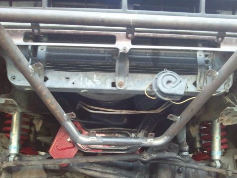 1982 Ford Bronco - The front underside of a vehicle is shown, with visible suspension parts and a horn. Text on the radiator support reads '1165'.