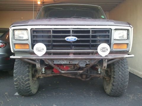 1982 Ford Bronco - This Ford Bronco's front end features a custom bumper and Hella lights, with the iconic Ford logo on the grille.