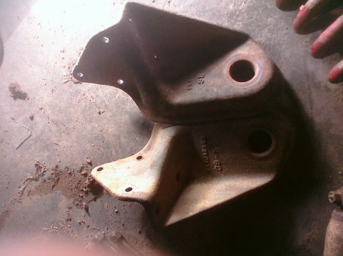 1995 Ford Bronco - Two rusty metal brackets are shown, possibly for a vehicle's lift system.