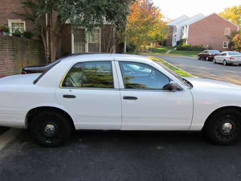 2003 Ford Crown Victoria - Side profile of a white 2003 Ford Crown Victoria parked on a street.