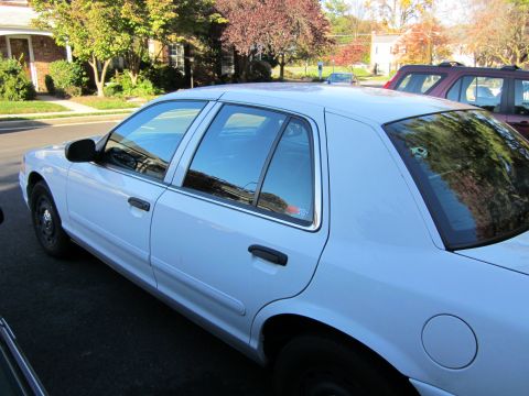 2003 Ford Crown Victoria - Side profile of a white 2003 Ford Crown Victoria parked on a street.