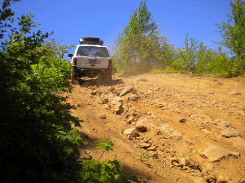 2005 Jeep Wrangler - A white Jeep Wrangler navigates a challenging, off-road path on a sunny day.