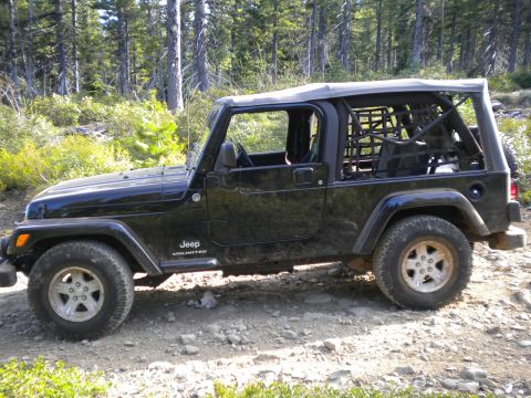 2005 Jeep Wrangler - Side view of a black 2005 Jeep Wrangler Unlimited on a forest road.