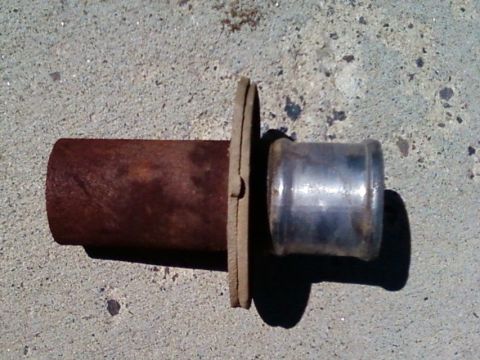 2006 Ford E350 - A close-up view of a rusted pipe connected to a metal fitting, resting on a concrete surface.