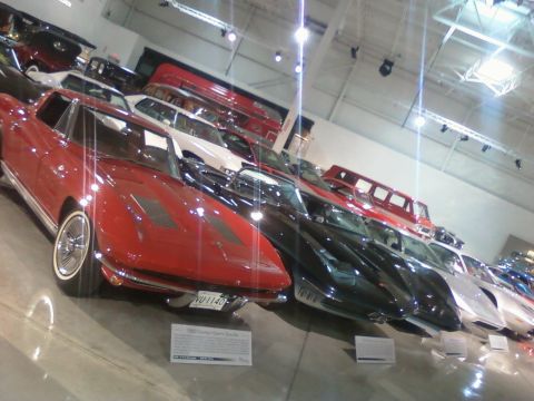 1971 Ford Ranchero - A row of classic cars are displayed indoors, with a bright red sports car in the foreground.