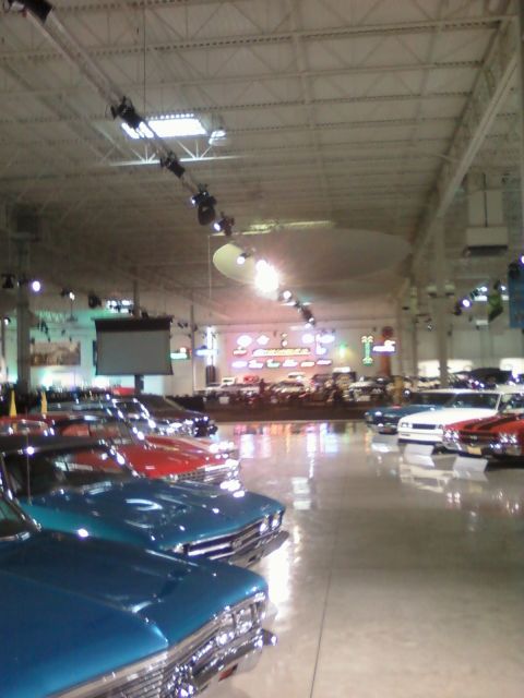 1971 Ford Ranchero - A collection of vintage automobiles are displayed indoors under bright lighting.