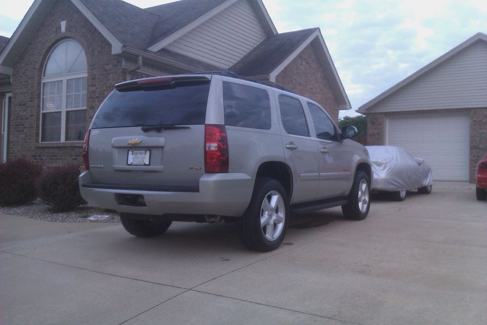 Rear view of a 2007 Chevrolet Tahoe parked in a driveway next to a covered car