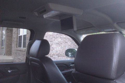 2007 Chevrolet Tahoe - The interior of a vehicle is captured, with a view of leather seats and a ceiling-mounted screen.