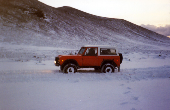 Red and white two-door SUV parked side-on in a snowy landscape at dusk